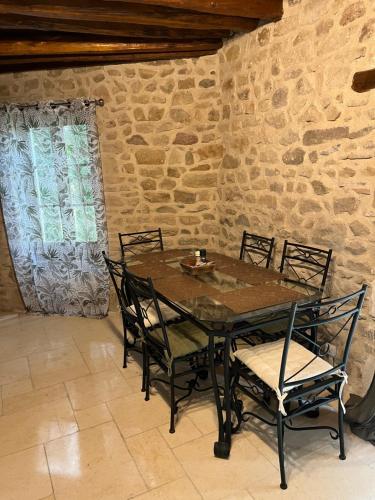 une table et des chaises dans une pièce avec un mur en pierre dans l'établissement maison Saint Berain sur Dheune, à Saint-Berain-sur-Dheune
