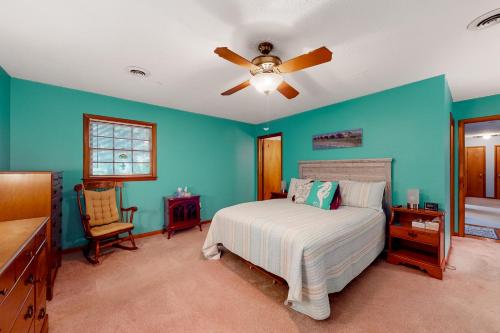 a bedroom with blue walls and a bed with a ceiling fan at Pine Knoll Nest in Pine Knoll Shores