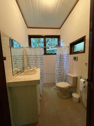 a bathroom with a toilet and a sink and a mirror at Casa linda no sítio in Duque de Caxias