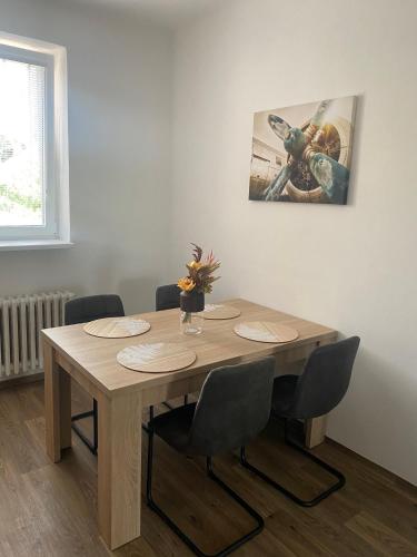 a wooden table with chairs and a picture on the wall at Černá Růže - Apartmán 3 in Plzeň