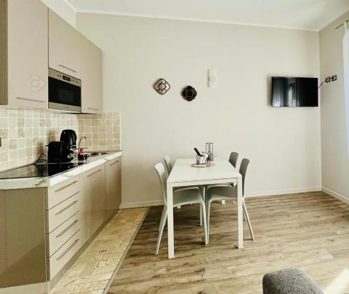 cocina blanca con mesa blanca y sillas en Garda Flow Holiday Home, en Lonato