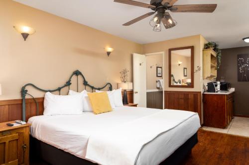 a bedroom with a large white bed with a ceiling fan at Prescott Pines Inn in Prescott