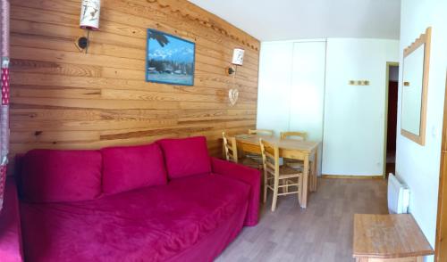 ein Wohnzimmer mit einem roten Sofa und einem Tisch in der Unterkunft Appartement coeur de station village Saint Francois Longchamp in Saint-François-Longchamp