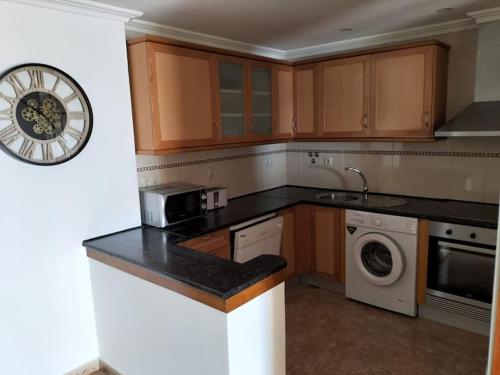 a kitchen with wooden cabinets and a clock on the wall at SEAVIEW ALBUFEIRA in Albufeira