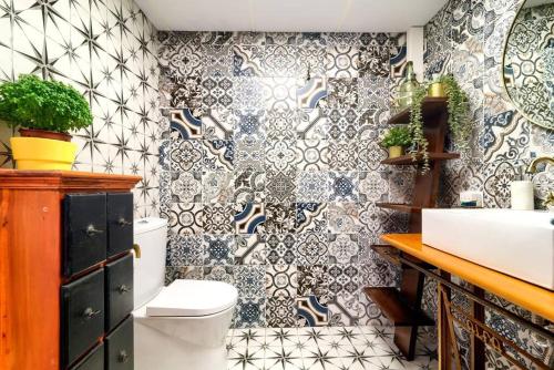 a bathroom with a toilet and a tiled wall at Cueva con jacuzzi a 20 minutos de Valencia in Benaguacil