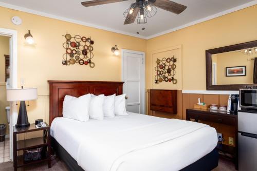 a hotel room with a large white bed and a mirror at Prescott Pines Inn in Prescott