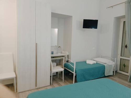 a small room with a bed and a desk with a monitor at Le vie del centro in Sciacca