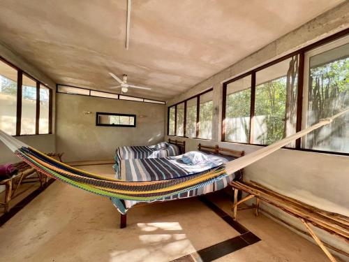a hammock in a room with a bed and windows at El Encanto - Hotel Boutique in Chichén-Itzá