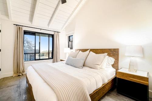 a white bedroom with a large bed and a window at Dune House in Manistee