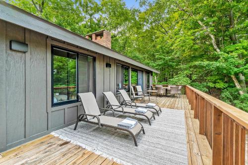 a deck with chairs and tables and windows at Dune House in Manistee