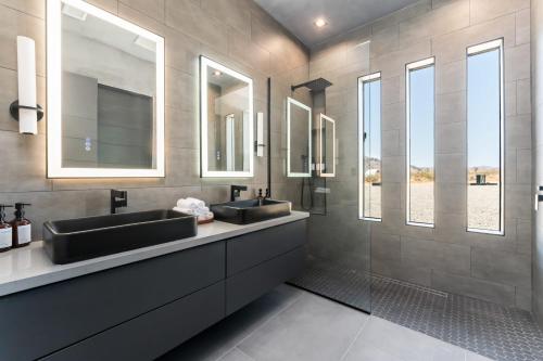 a bathroom with two sinks and two mirrors at Black C House- Pool & Spa in Joshua Tree