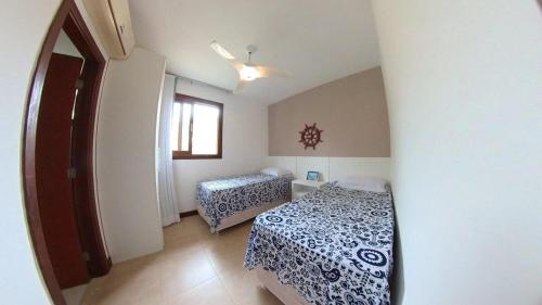 a bedroom with two beds and a window at Reserva Imbassaí Apartamento 3 suites vista mar Td6201 in Mata de Sao Joao