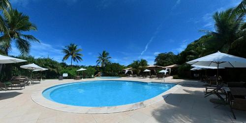 a large swimming pool with umbrellas and chairs at Reserva Imbassaí Apartamento 3 suites vista mar Td6201 in Mata de Sao Joao