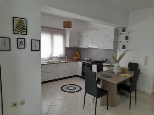 una cucina con tavolo e sedie e una cucina con armadietti bianchi di Giotouli Apartment a Afantou