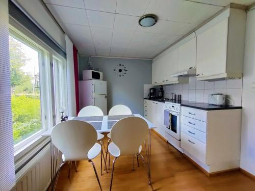 a kitchen with white cabinets and a table and chairs at Polku Apartaments in Imatra