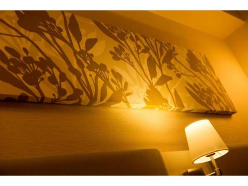 a painting on a wall above a bed with a lamp at QUEEN'S HOTEL CHITOSE - Vacation STAY 67717v in Chitose