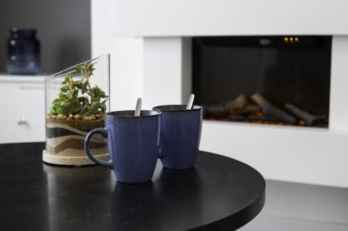 dwa niebieskie kubki do kawy siedzące na stole w kuchni w obiekcie Elegant 3 bedroom House w mieście Leigh
