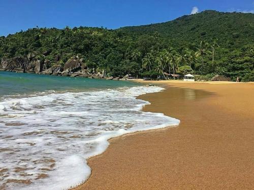 a sandy beach with waves coming in from the ocean at Chalés da Barra Ilhabela in Ilhabela