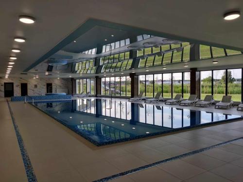 una grande piscina in un edificio con sedie di Apartamenty AMBER -Marina Dziwnów - basen, jacuzzi i sauny a Dziwnów