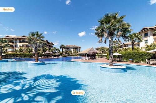 a large swimming pool with palm trees in a resort at Térreo com churrasqueira no VG Sun por Tactu in Cumbuco