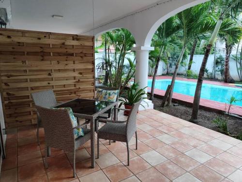 een patio met een tafel en stoelen en een zwembad bij Artists house Family unit in Rivière Noire