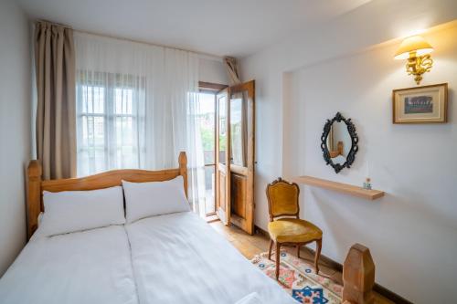 a bedroom with a bed and a chair and a window at Four Riders Guest House in Veliko Tŭrnovo