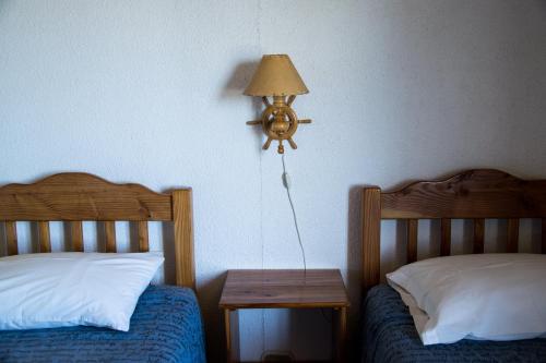 a bedroom with two beds and a table with a lamp at Hostal Mundo Nuevo in Ancud