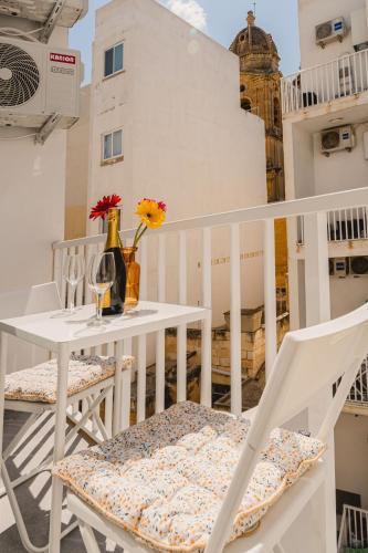 a white table and chairs on a balcony with flowers at Stylish 2BED Unit 50m from Seafront! WiFi and Washer in Il-Gżira