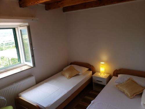 Duas camas num pequeno quarto com uma janela em Villa Kula em Bajagić