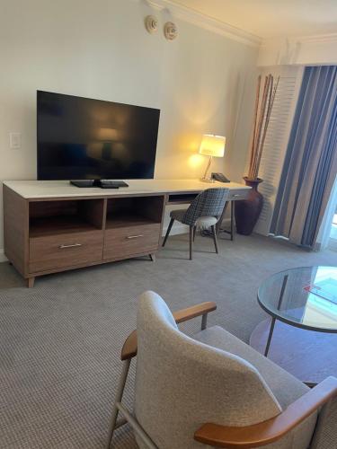 een woonkamer met een bureau, een tv en stoelen bij The Atlantic Hotel & Spa Condo in Fort Lauderdale