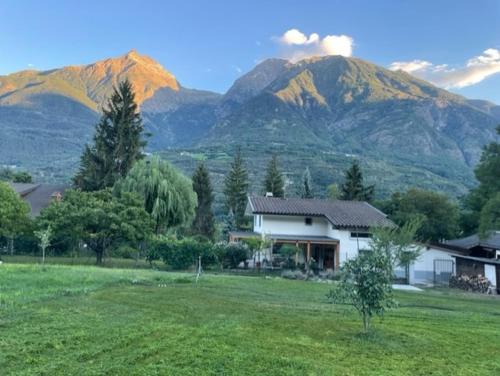 a house in a field with mountains in the background at La Casina di Oscar ad AO V Combe VDA QUART 0014 e 00I6 in Quart