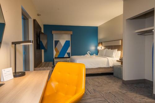 a hotel room with a bed and a yellow chair at Holiday Inn Express Hotel & Suites Tampa-Oldsmar by IHG in Oldsmar