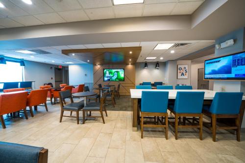 a dining room with tables and chairs and a flat screen tv at Holiday Inn Express Hotel & Suites Tampa-Oldsmar by IHG in Oldsmar