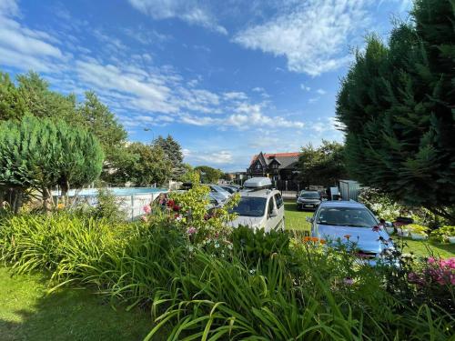 a group of cars parked in a yard with flowers at Pokoje gościnne u Małgosi in Jarosławiec