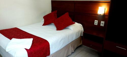 een slaapkamer met een bed met rode kussens erop bij Hotel Las Pascuas in Tarija