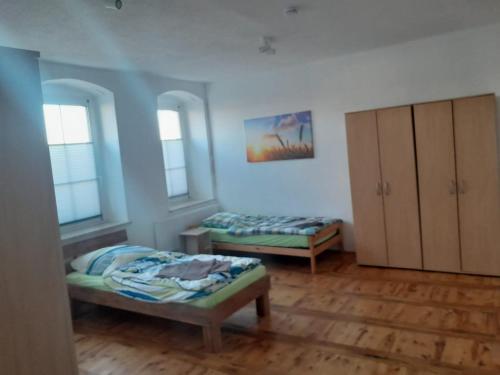 a room with two beds and a cabinet and windows at Monteurswohnung Place2stay in Großenhain in Großenhain