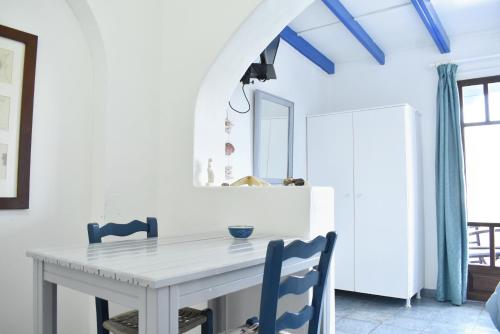 uma sala de jantar com uma mesa branca e cadeiras azuis em Martinos Studios em Kithnos
