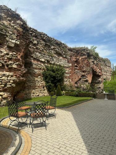 a stone wall with a table and chairs in a courtyard at Villa Paris in Hisarya
