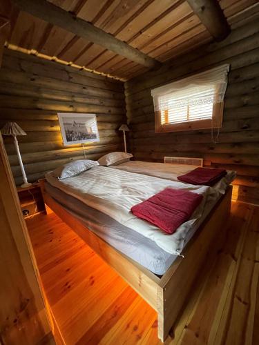 a large bed in a log cabin with a window at Nuustakumajad in Otepää