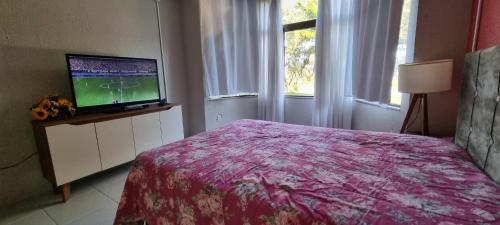 a bedroom with a bed and a flat screen tv at Sítio com piscina Hidromassagem com acesso ao Rio Mampituba in Passo de Torres