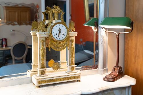eine Uhr, die auf einem Tisch vor einem Spiegel sitzt in der Unterkunft Demeure Belle Epoque in Reims