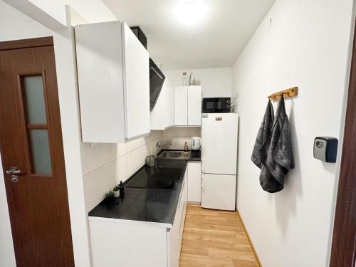 a small kitchen with white cabinets and a refrigerator at Anielewicza 26 Rooms in Warsaw