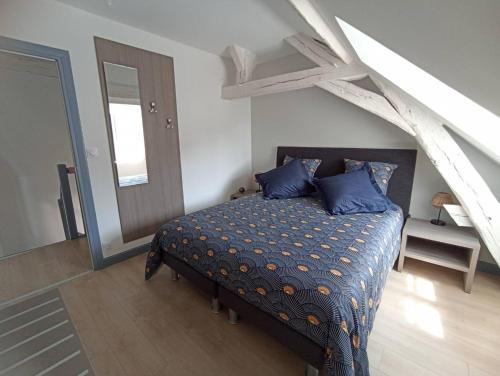 a bedroom with a bed with blue pillows on it at Le palais duplex in Autun