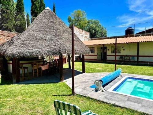 a house with a pool and a straw umbrella at Casa de descanso alberca climatizada in Atlixco