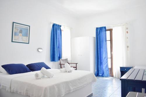 two beds in a white room with blue curtains at Martinos Studios, Merihas port in Kithnos