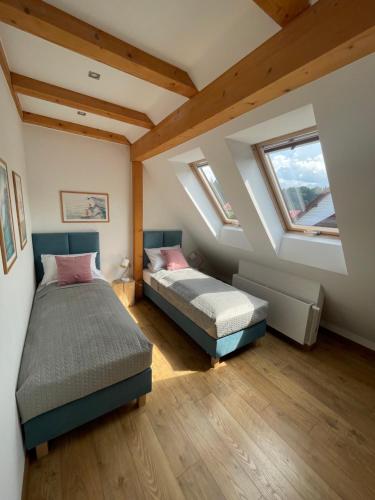 a attic bedroom with two beds and two windows at SURF STYLE APARTAMENT in Muszyna