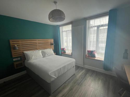 a bedroom with a bed with blue walls and windows at No.5 in Derry Londonderry
