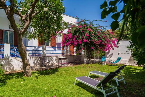 einen Stuhl und eine Bank in einem Hof mit rosa Blumen in der Unterkunft Le Vele Mondello, villa a due passi dal mare in Mondello