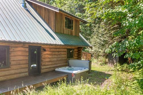 a wooden cabin with a hot tub on the porch at Avlägsen Chalet in Deming
