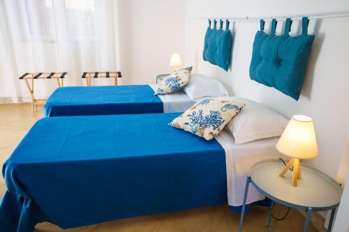 two beds in a room with blue sheets and pillows at Le Vele Mondello, villa a due passi dal mare in Mondello